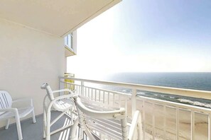 Ein Balkon mit weißen Stühlen und Gel änder mit Blick auf einen Strand.