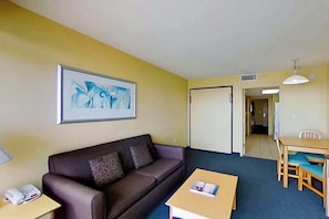 A room with a sofa, a small table, a dining table with chairs, and a framed picture on the wall. - Bay Watch Resort 1804 (North Myrtle Beach)
