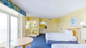 Une chambre d’hôtel avec deux lits, une table à manger, un coin cuisine et une salle de bain.
