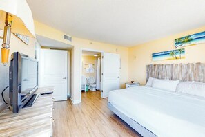 Una habitación de hotel con cama, televisión, baño y un cuadro en la pared.