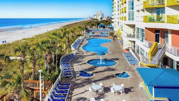 A resort with a pool area, lounge chairs, and a view of the beach. - Bay Watch Resort 1815 (North Myrtle Beach)