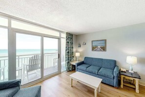Ein Zimmer mit Balkon, einer Couch, einem Tisch und einer Lampe.