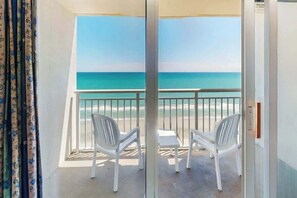 A balcony with a view of the beach and ocean, white plastic chairs, and a small table. - Bay Watch Resort 1839 Oceanfront (North Myrtle Beach)