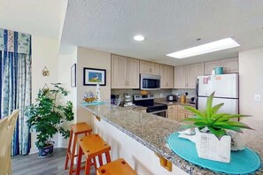 A modern kitchen with granite countertops, stainless steel appliances, and bar stools.