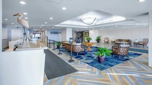 A hotel lobby with a reception desk, seating area, and a large bird sculpture. - Bay Watch Resort 1906 (North Myrtle Beach)