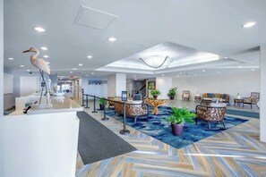 A hotel lobby with a reception desk, seating area, and a large bird sculpture. - Bay Watch Resort 1906 (North Myrtle Beach)