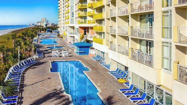 A hotel with multiple swimming pools, sun loungers, and a beach view. - Bay Watch Resort 1906 (North Myrtle Beach)