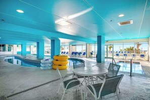 An indoor swimming pool area with lounge chairs and a table. - Bay Watch Resort 1919 (North Myrtle Beach)