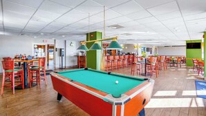 Une table de billard recouverte d’un drap vert, entourée de chaises rouges.