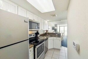 A compact kitchen with white cabinets, a built-in microwave, and a stove. - Bay Watch Resort 1920 (North Myrtle Beach)