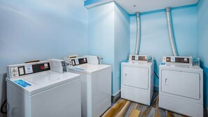 A laundry room with four white washing machines, two dryers, and a blue wall. - Bay Watch Resort 1920 (North Myrtle Beach)