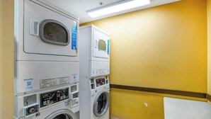 A laundry room with stacked washers and dryers, a payment terminal, and a wall-mounted mirror. - Bay Watch Resort 1921 (North Myrtle Beach)