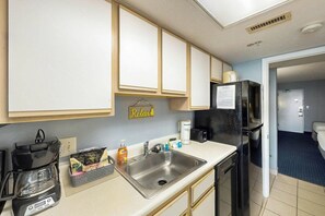 A compact kitchenette with a coffee maker, a sink, and a refrigerator. - Bay Watch Resort 1934 (North Myrtle Beach)