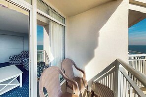 A balcony with a view of the sea, a white table, and two chairs. - Bay Watch Resort 1934 (North Myrtle Beach)
