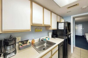A compact kitchen with a coffee maker, sink, and refrigerator. - Bay Watch Resort 1934 (North Myrtle Beach)