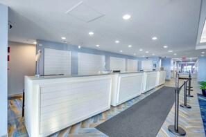 A reception area with a counter, a plant, and a patterned floor. - Bay Watch Resort 1934 (North Myrtle Beach)