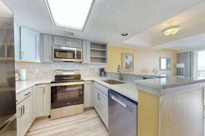 A modern kitchen with built-in appliances, a dishwasher, and a large island. - Camelot by the Sea 0809 (Myrtle Beach)