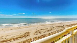 A beach with a clear sky, a sandy shore, and a railing in the foreground. - Camelot by the Sea 0809 (Myrtle Beach)