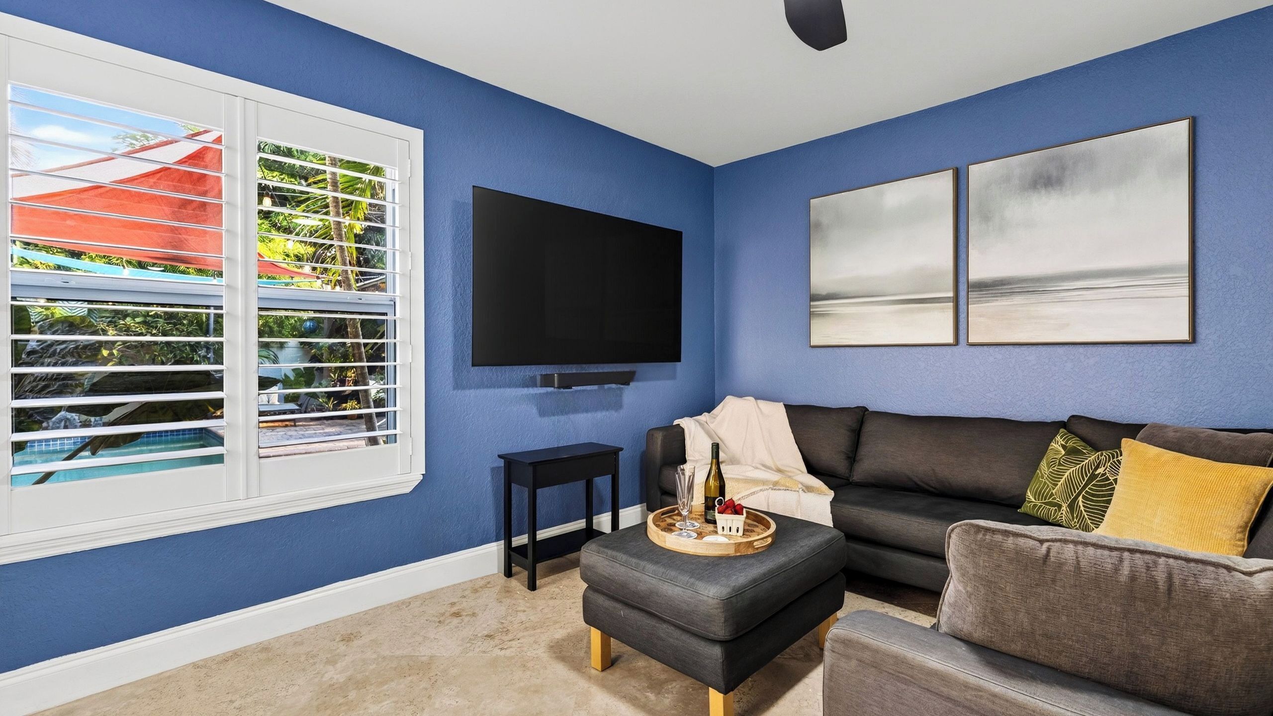 A living room with a blue wall, a flat-screen TV, a sofa, and a coffee table with a tray of items.