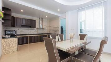 Una cocina moderna con zona de comedor, que incluye horno empotrado, microondas y campana extractora de acero inoxidable.