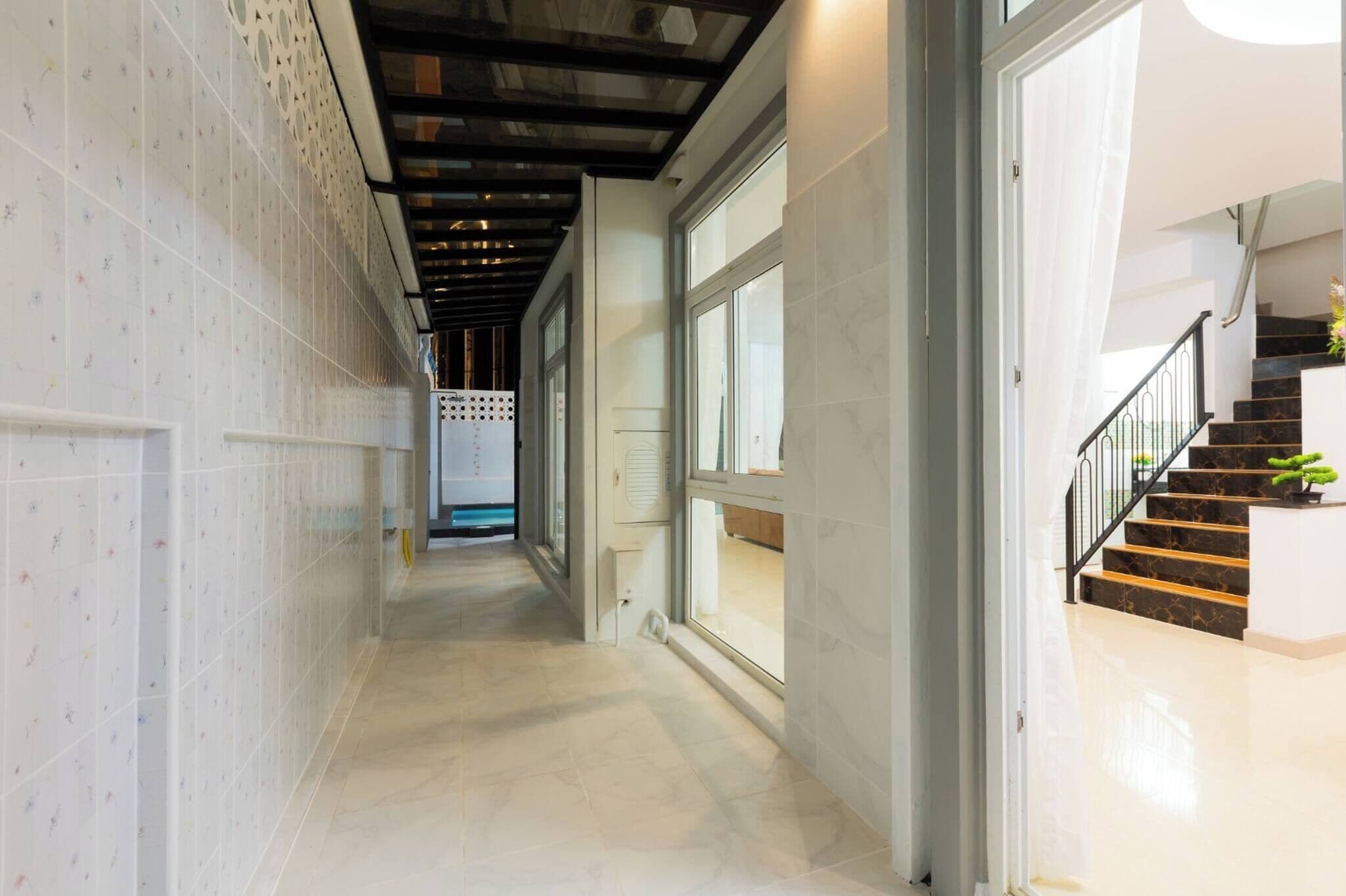 A hallway with a tiled floor, a staircase with a black railing, and a door leading to another room.