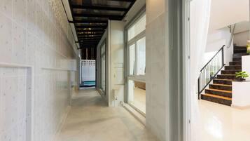 A hallway with a tiled floor, a staircase with a black railing, and a door leading to another room.