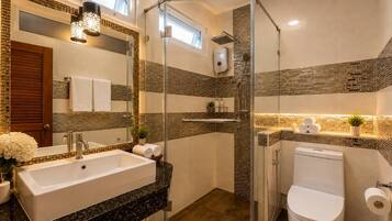 A modern bathroom with a glass-enclosed shower, a freestanding bathtub, and a toilet.