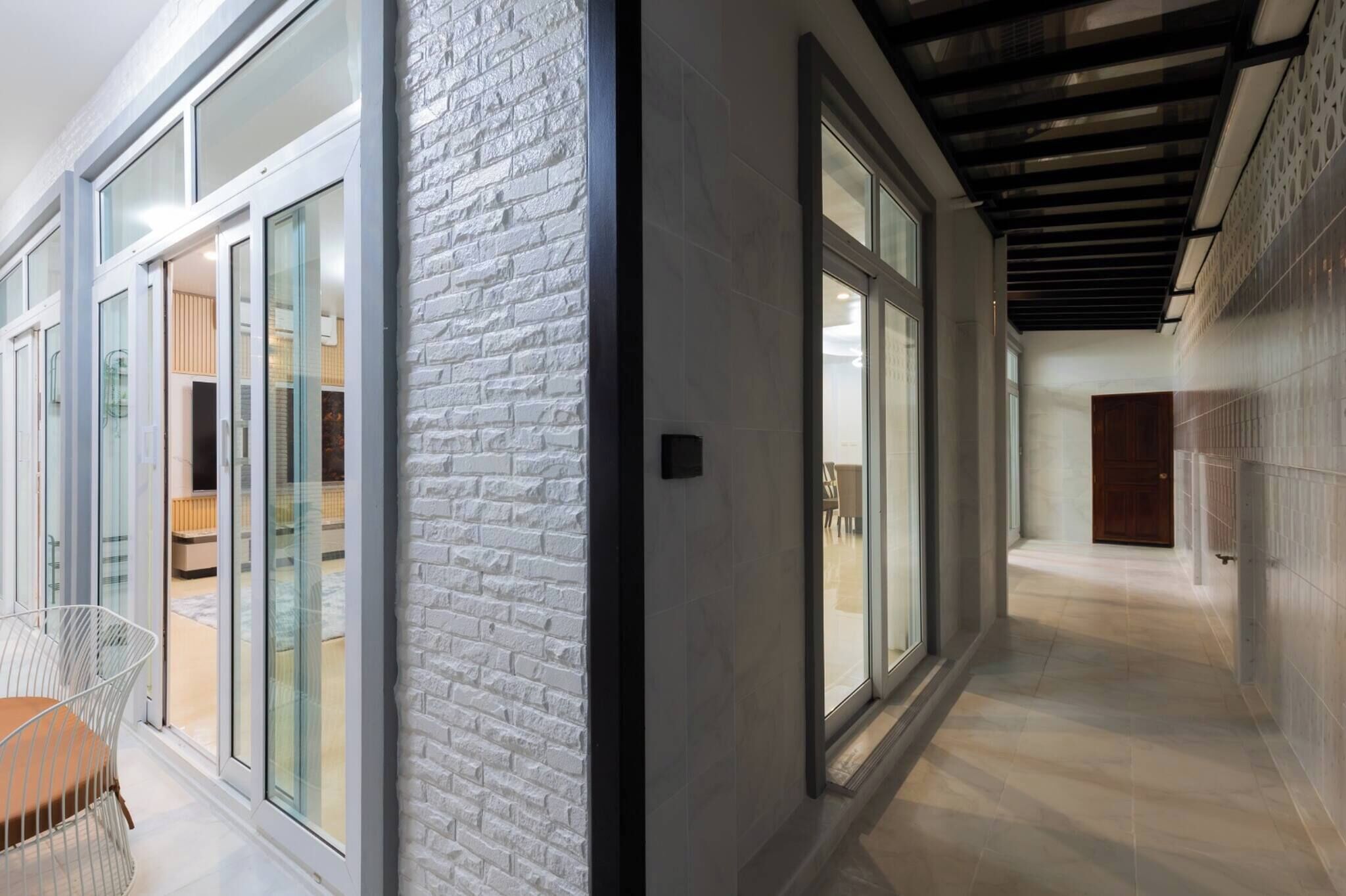 Un pasillo moderno con puertas de vidrio, una pared de ladrillo decorativa y suelo de baldosas.