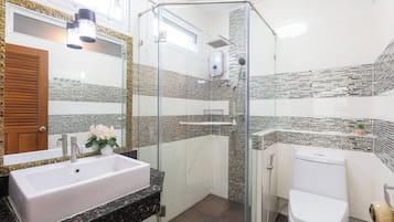 A modern bathroom with a glass-enclosed shower, a white sink, and a toilet.