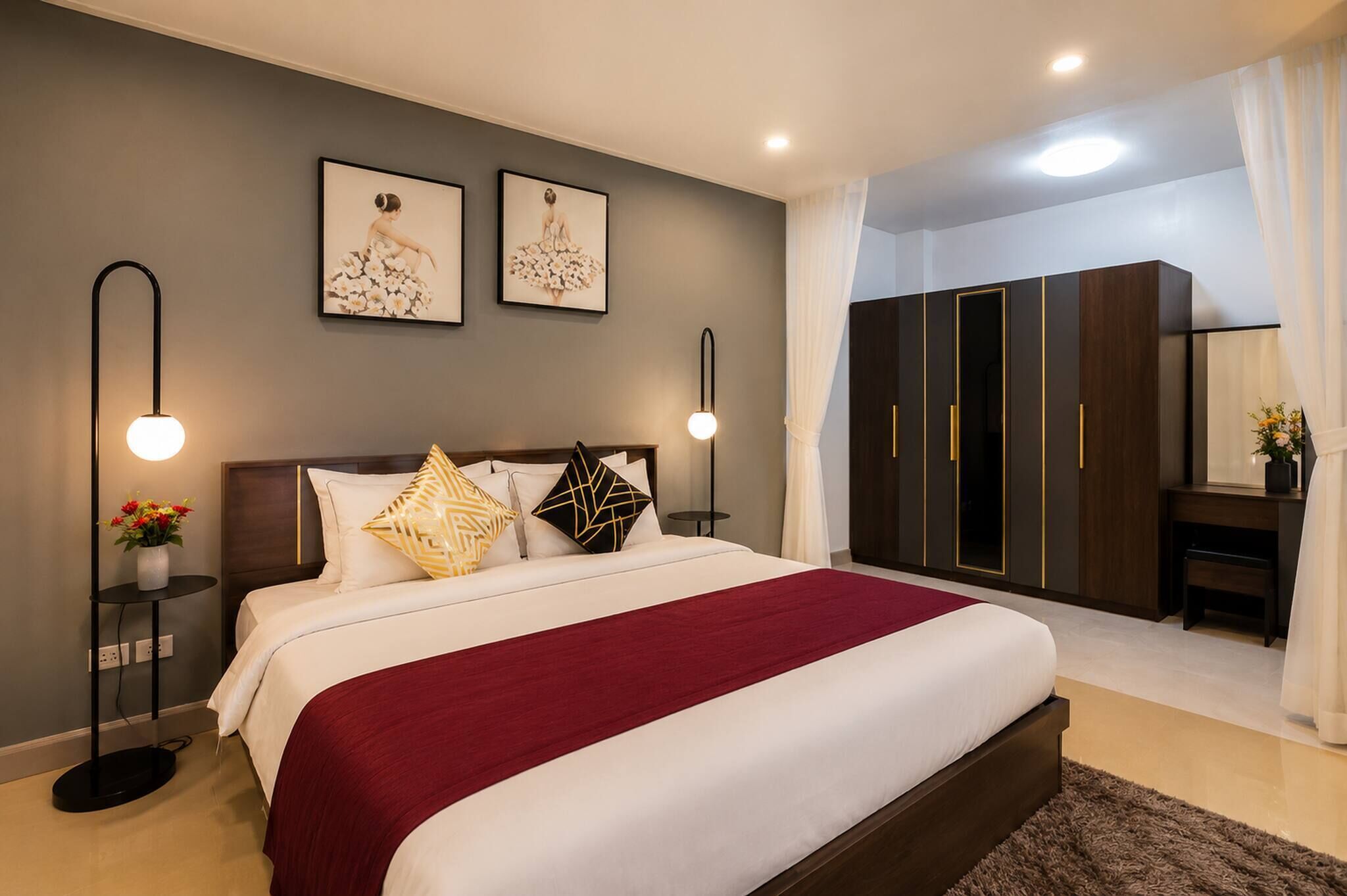A modern bedroom with a large bed, bedside tables, a wardrobe, and a desk with a chair.
