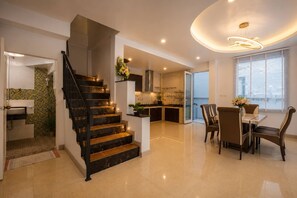 A modern kitchen with a central island, a dining area with a table and chairs, and a staircase leading to an upper floor. - Luxury4br Pool Villawalk to Patongbeachrooftop BBQ (Patong)