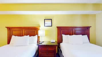 A hotel room with two beds, a nightstand, a lamp, and a framed picture on the wall.