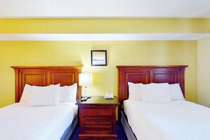 Ein Hotelzimmer mit zwei Betten, einem Nachttisch, einer Lampe und einem gerahmten Bild an der Wand.