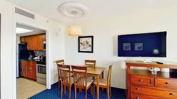 A compact room with a dining table, chairs, a television, and a dresser.