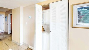 Um corredor com uma porta branca, uma lavanderia e um quadro na parede.