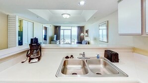 Une chambre d’hôtel avec une grande fenêtre, un lavabo avec un miroir, une machine à café et un grille-pain.