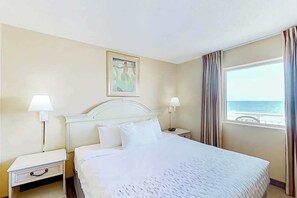 Une chambre d’hôtel avec un lit, deux tables de chevet avec des lampes, un tableau au mur et une fenêtre avec des rideaux.