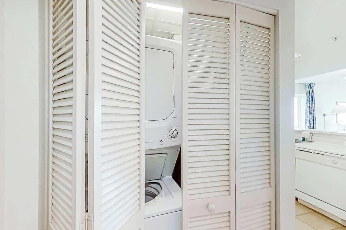 Ein Waschraum mit Waschmaschine, Trockner und einem weißen Schrank.