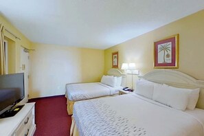 Ein Hotelzimmer mit zwei Betten, einem Fernseher und Bildern an den Wänden.