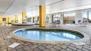 An indoor swimming pool with tiled flooring, lounge chairs, and a ceiling with a grid pattern. - Camelot by the Sea 0516 (Myrtle Beach)