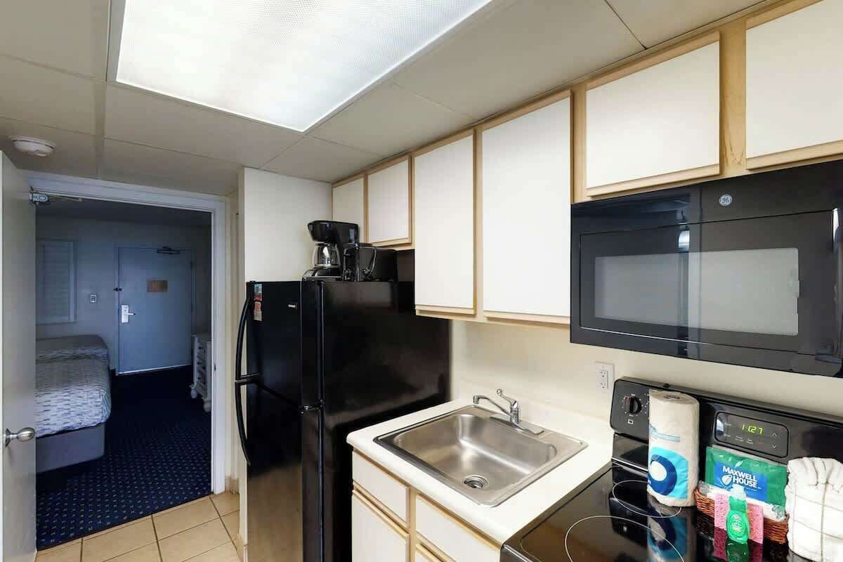 A compact kitchen with a refrigerator, microwave, and a sink.