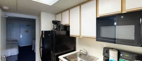 Una cocina compacta con refrigerador, microondas y pileta.