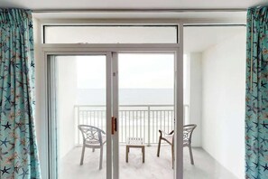 Ein Balkon mit weißer Geländer, zwei Stühle und ein kleiner Tisch.