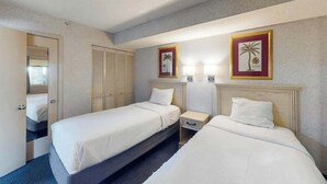 A hotel room with two beds, a bedside table, a nightstand, a mirror, and two framed pictures on the wall. - Camelot by the Sea 0617 (Myrtle Beach)