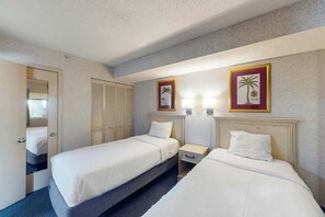 Ein Hotelzimmer mit zwei Betten, einem Nachttisch, einem Spiegel und zwei gerahmten Bildern an der Wand.