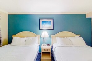 Ein Hotelzimmer mit zwei Betten, einem Nachttisch mit Lampe und einem gerahmten Bild an der Wand.