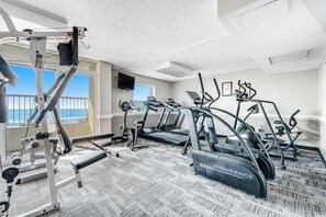 A gym with treadmills, a weight machine, and a bench. - Camelot by the Sea 1016 (Myrtle Beach)