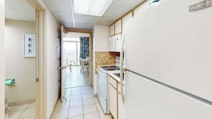 Ein enger Flur führt zu einer Küche mit Kühlschrank, Herd und Mikrowelle.