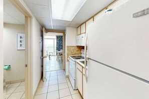 Ein enger Flur führt zu einer Küche mit Kühlschrank, Herd und Mikrowelle.