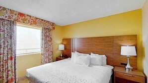 Una camera d'hotel con un letto grande, due comodini con lampade e una finestra con tende.